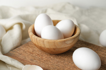 Bowl with fresh raw eggs on table