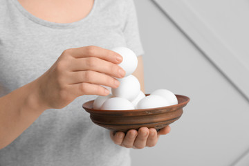 Woman with bowl of fresh raw eggs, closeup