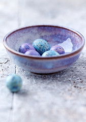 Colorful quail egg in a ceramic cup. Bright stone background. 