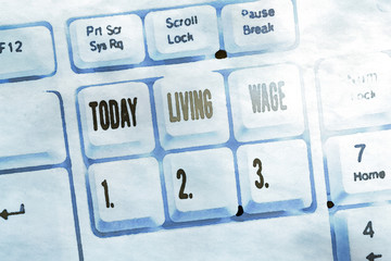Writing note showing Living Wage. Business concept for wage that is high enough to maintain a...