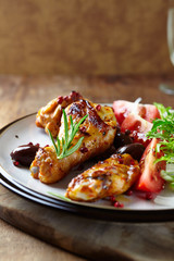 Grilled chicken pieces with kalamata olives, tomatoes, endive and fresh rosemary. Rustic wooden background. Close up.