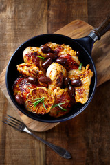 Grilled chicken pieces with kalamata olives and fresh rosemary. Rustic wooden background. Top view. 