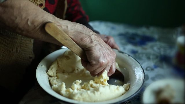 Strain out butter from whey. old woman's hand with a wooden spoon prepares butter.