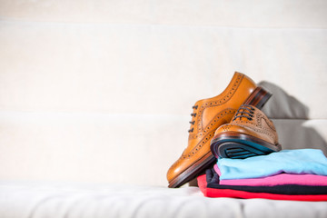 Pair of Male Full Brogued Tan Oxford Shoes Placed on Top of Heap Of Colorful Clothing