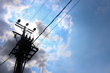 Utility pole supporting overhead power line cables against blue sky as copy space
