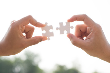 closeup hand of connecting jigsaw puzzle with sunlight effect, business solutions, success and strategy concept