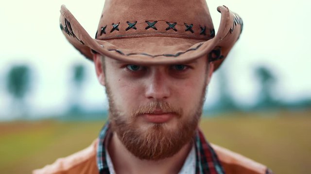 Portrait cowboy tips cowboy hat towards camera look at camera on field vintage west wild adventure agriculture animal beauty portrait face close up portrait