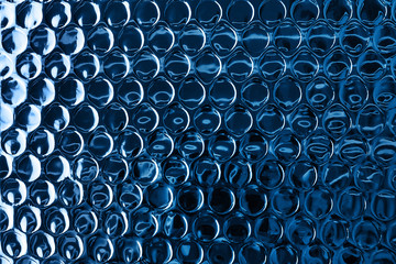 Shiny blue foil surface with round impressions for textured background. Color of the year 2020 concept. Copy space.