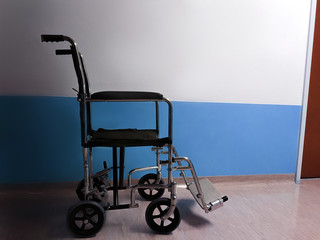 an empty wheelchair stands in the dark, dreary hospital corridor. Low-exposure photography