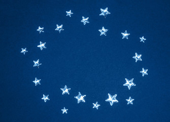 Beautiful shining silver stars with embossed transparent top arranged in circle on trendy blue background. Color of the year 2020 concept. Copy space.