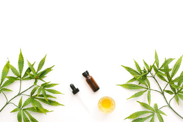 Glass bottles with CBD oil, THC tincture and hemp leaves on a white background. Flat lay,...