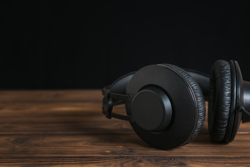 Obraz na płótnie Canvas Beautiful black headphones on wooden table on black background.