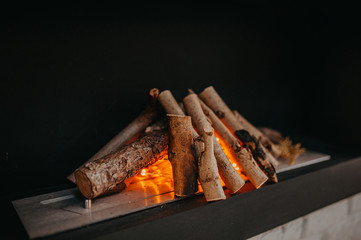 home artificial fireplace, firewood stacked in a bonfire with a garland inside