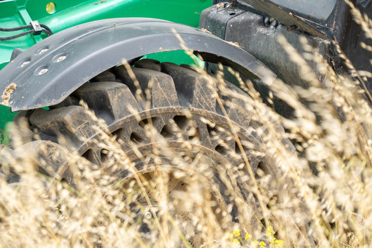 Large Green Tractor Heavy Equipment No Flat Tire Through Wheat Field Close Up.