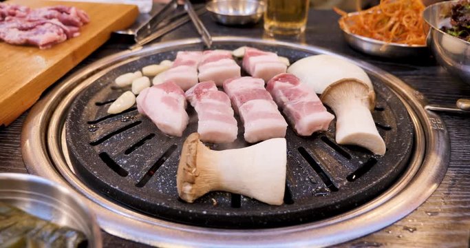 Pork belly, mushrooms and garlic grilling on a Korean barbecue.
