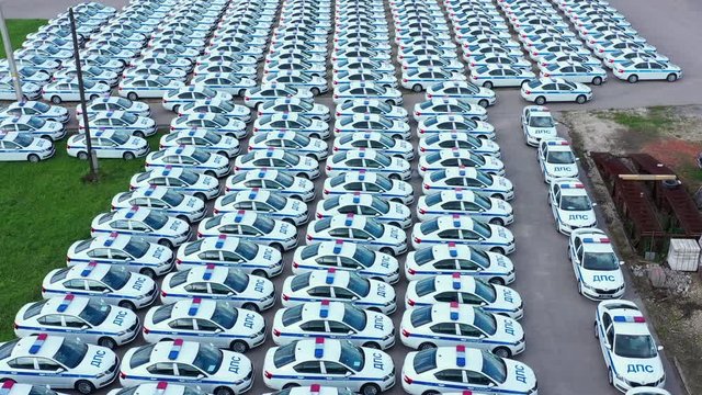 Many traffic police cars standing on parking lot aerial view. Identical police dps patrol cars in parking lot from drone above.