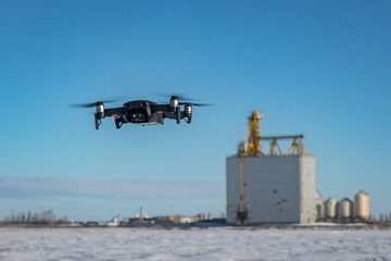 Black Drone Hovering Near Old Grain Elevator in Winter