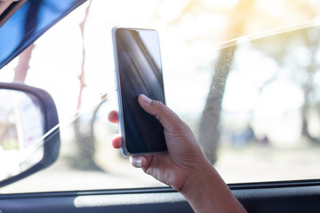 The hand of driver is using a mobile phone to help navigate or GPS while parking on the side of the...