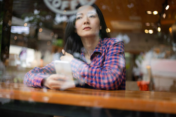 using cell phone.hand holding texting message on screen mobile chatting friend ,search internet information sitting on desk in cafe.technology device contact communication connecting people concept