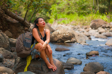young beautiful and happy Asian Korean woman carrying backpack trekking on mountains crossing river enjoying holiday nature and fresh environment hiking cheerful