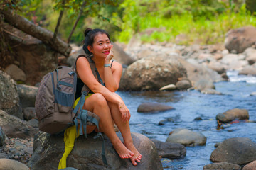young beautiful and happy Asian Chinese woman carrying backpack trekking on mountains crossing river enjoying holiday nature and fresh environment hiking cheerful