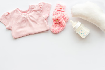 Baby background - pink color. Clothes, booties and accessories for newborn girl on white table top-down frame copy space