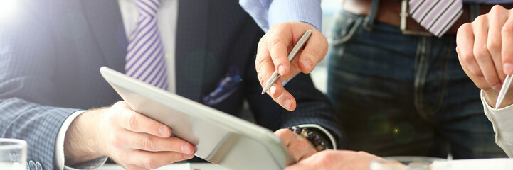 Male hand pointing in tablet computer during business meeting with customers and clients