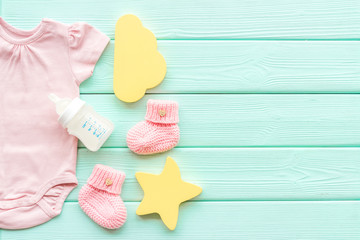 Baby background - pink color. Clothes, booties and accessories for newborn girl on green wooden table top-down frame copy space