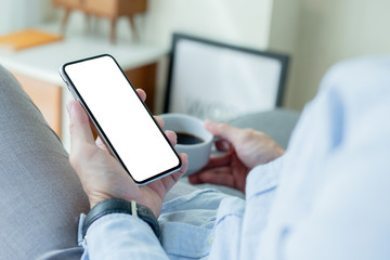 Mockup image blank white screen cell phone.men hand holding texting using mobile on desk at home office. background empty space for advertise text.people contact marketing business and technology 