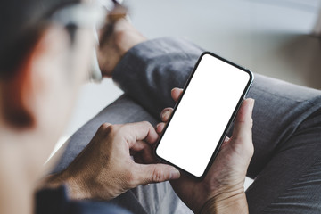 Mockup image blank white screen cell phone.men hand holding texting using mobile on desk at home...