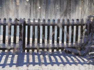 Blurry view of a wooden fence with the tops and bottoms covered with fresh snow