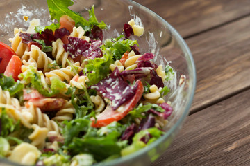Vegetable salad with pasta and cheese on wooden background. Vegetarian, recipe, culinary, cooking concept. Close-up, copy space