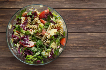 Vegetable salad with pasta and cheese on wooden background. Vegetarian, recipe, culinary, cooking concept. Top view, close-up, copy space