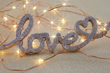 Love concept. Valentine's Day. The word love and a shining garland on a  gold glitter...