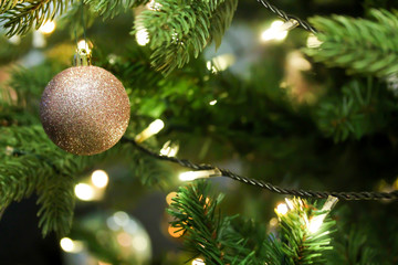 Fototapeta na wymiar Christmas tree decorated with pink glittering baubles. Artificial fir tree with led light garland. Festive holiday background.