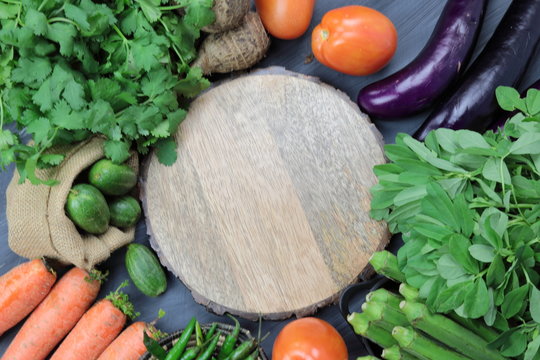 Indian vegetables of Tomatoes, carrots, Yams, Pointed gourd, Green chilies, Methi leaves, cilantro, and egg plants with copy space.