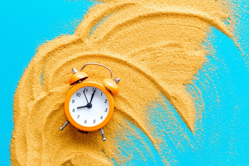 Deadline concept. Clock on sand on blue background top-down