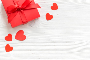 Gift to a sweetheart on Valentine's Day. Red present box near hearts on white wooden background top-down copy space