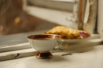 Breakfast on the old windowsill. Cabbage pie and coffee with milk on cracked painted wood. old window interior
