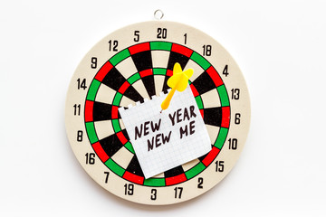 New year new me - motivation concept - text attached by dart to dart board on white background top-down