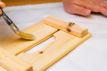 Girl varnishes a wooden detail.