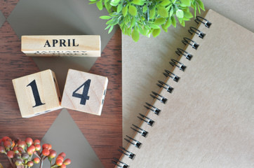 April 14. Date of April month. Number Cube with a flower and notebook on Diamond wood table for the...