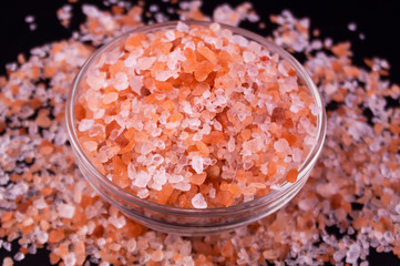 Fototapeta na wymiar Himalayan pink rock salt in bowl on black table, top view