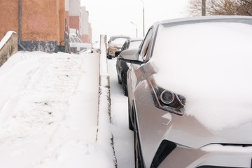 Snowfall in the city cars in the snow on the street