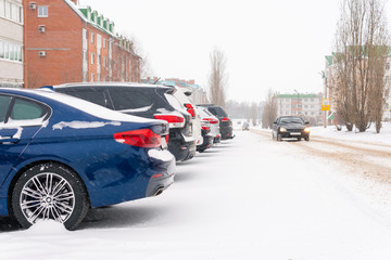 Snowfall in the city cars in the snow on the street