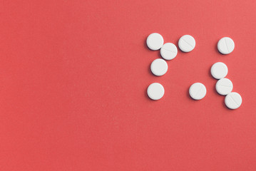 Round pills scattered on a red background. Top view, copy space. Pharmacy concept