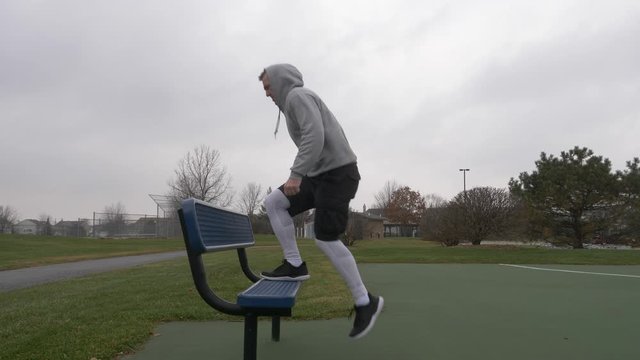 Man working out, strength training, exercising, getting fit, doing leg exercises step ups outside on a cold day.