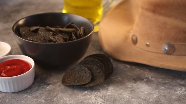 Woman hand takes black Mexican chips nachos and dips in a sause salsa