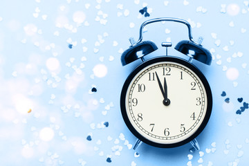 Alarm clock on a blue background with small hearts. The concept of the time of love, the time of date, the wedding, the day of St. Valentine, New Year