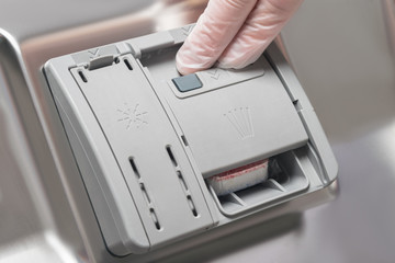 man's hand closes a dishwasher dishwashing detergent container